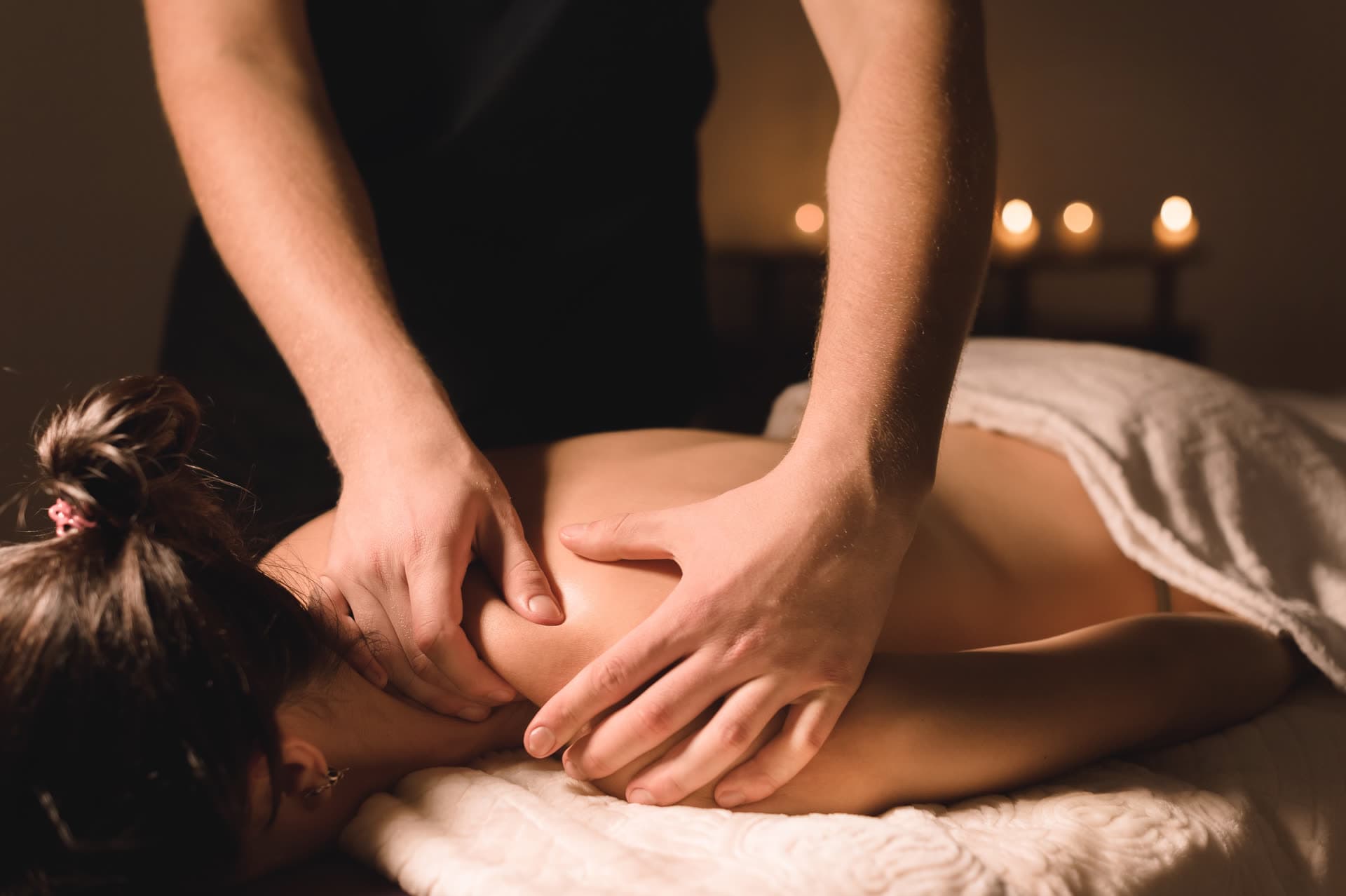 Relaxing candlelit Swedish massage with long, gentle strokes across the shoulders